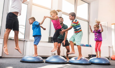 Small children jumping on bosu balls on training class.